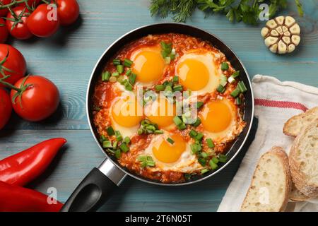 Delicious Shakshuka in frying pan served on light blue wooden table, flat lay Stock Photo