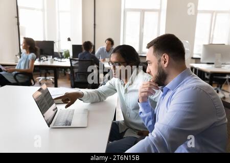 Two multiethnic employees watching project presentation on laptop Stock Photo