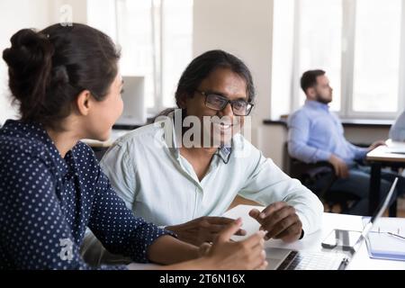 Two happy Indian business coworkers talking at laptop computer Stock Photo