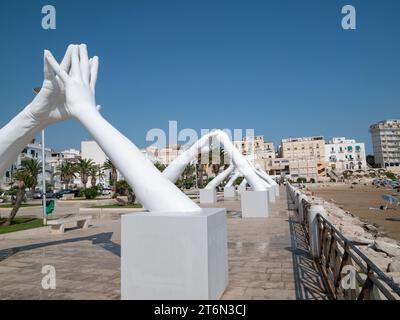 Vieste, Italy - 25 August 2023:View of Building Bridges, six pairs of giant hands, 15 meters high and joined, in the heart of Vieste on the Marina Pic Stock Photo