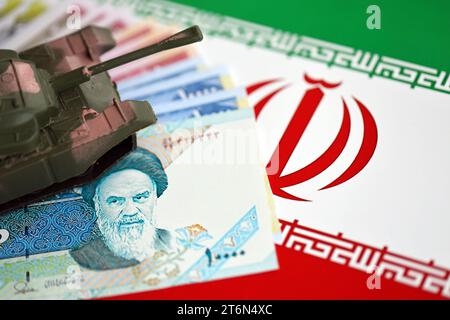 Iranian army toy tank drive on iranian bills of rial currency on flag of Islamic Republic of Iran close up Stock Photo