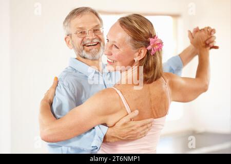 Senior couple, dancing and happiness in home, love and ballroom for fun, touch and romantic. Retirement, bonding together and smile for husband, wife Stock Photo