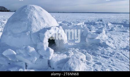 igloo and snow shelter in high snowdrift with mountains peaks on background Stock Photo