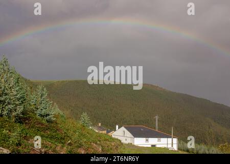 rainbow over the mountains at sunset with a grey sky Stock Photo