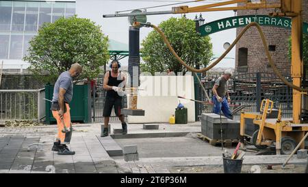 Skilled stone layers put down a new sidewalk at a construction site near the Chocolate Factory in Cologne, Germany. Stock Photo