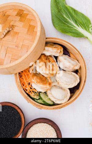 Close up chinese steamed dumplings with salad steamer basket with black white sesame seeds Stock Photo