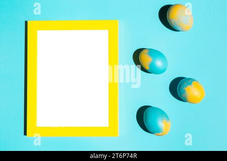 Colourful easter eggs with blank frame blue table Stock Photo