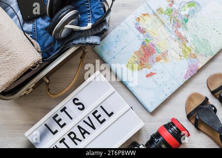 Overhead view travelling bag map camera pair footwear wooden table Stock Photo