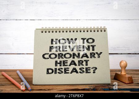 How to Prevent Coronary Heart Disease. Green notepad on wooden texture table and white background. Stock Photo