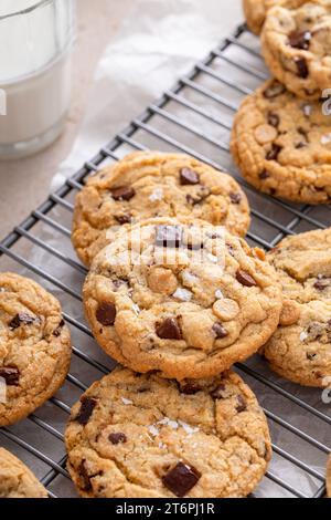 Chocolate chip cookies on a cooling rack with flaky salt served with cold milk close up shot Stock Photo