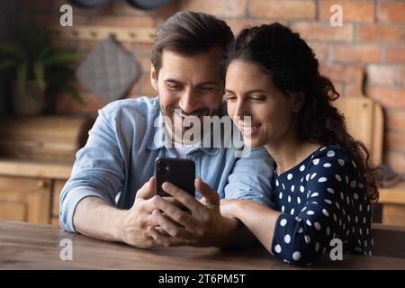 Close up smiling young couple hugging, using smartphone together Stock Photo