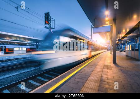 Blurred high speed train on the modern railway station at night Stock Photo