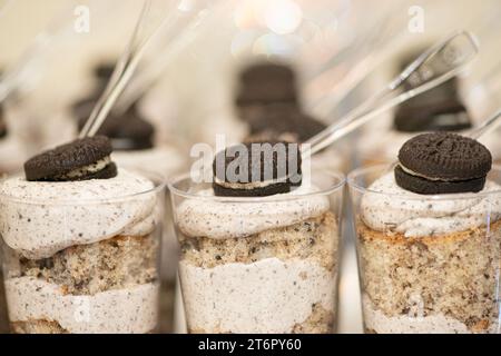 Rows of chocolate and whip cream desserts in little plastic cups with chocolate cookie toppings at dessert table Stock Photo