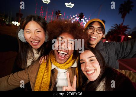 Excited Christmas selfie of multicultural young group friends. Four happy colleagues taking photo. Stock Photo