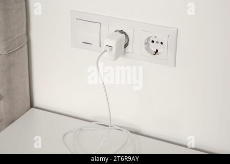 Plug in power socket and light switch on white wall indoors Stock Photo