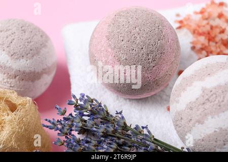 Bath bombs, towel, lavender and loofah sponge on pink background, closeup Stock Photo