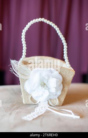 Wicker basket with pearl handle and white flower decoration purple background Stock Photo