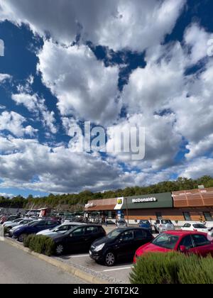 Rome, Italy - 09 august 2023: Large parking lot with cars near the McDonalds building surrounded by trees Stock Photo