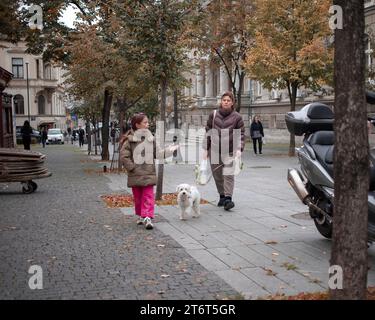 Belgrade, Serbia, Nov 10, 2023: Woman with a daughter walking dog down the Master's Square (Magistarski Trg) in Zemun Stock Photo