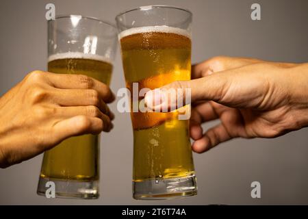 Cheers concept. Glasses with fresh lager draft beer with foam. Men hipster  hold mugs filled with cold tasty beer in bar. Friday leisure tradition. Beer  mugs at bar counter defocused background Stock