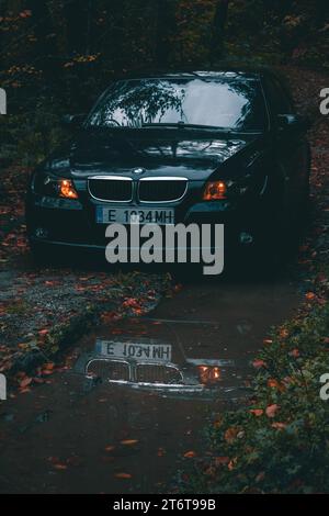 Bulgaria - 11,12,2023: Forest photo session on a car with reflections from a puddle. Stock Photo