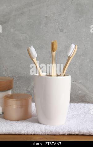 Bamboo toothbrushes in holder and towel on white background Stock Photo ...