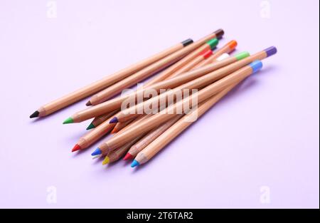 Many colorful pastel pencils on violet background. Drawing supplies Stock Photo