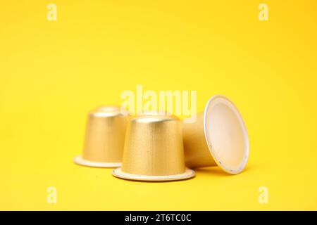 Three coffee capsules on yellow background, closeup Stock Photo