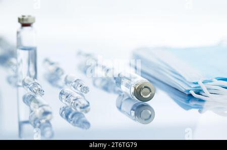 Medical ampoules for injection and disposable masks over desk. Scattered glass ampoules with medicine on the table. Stock Photo