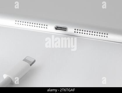 View of Apple Lightning cable and gadget on a white table with empty space, close-up. Stock Photo