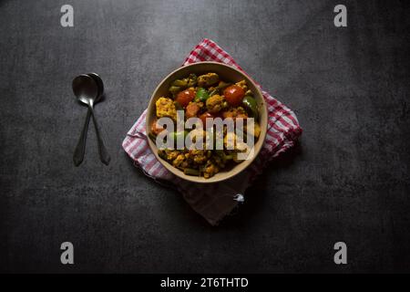 Indian main course dish mixed veg curry prepared with carrots, cauliflower, beans, capsicum and paneer or cottage cheese served in a bowl. Top view Stock Photo