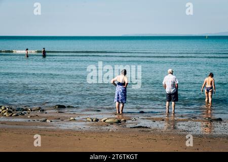 People paddle in the shallow waters of Abersoch in Gwynedd, North Wales in the UK Stock Photo