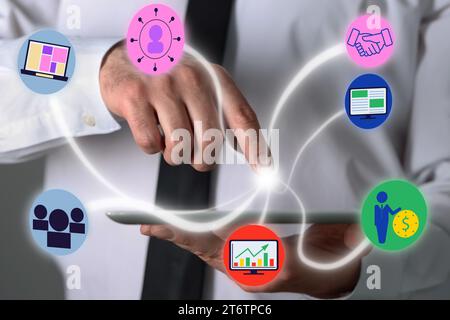 Marketing strategy. Man using tablet computer, closeup. Different virtual icons appearing before touch Stock Photo