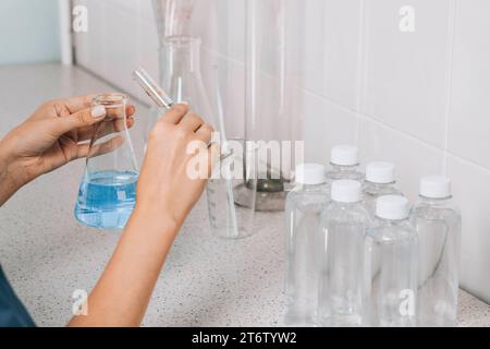 Women's hands in the laboratory examines the quality of water with a glass tube filled with a blue chemical liquid for research and analysis in the Stock Photo