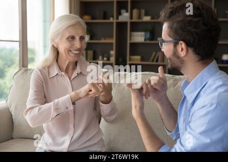 Grownup son communicates with senior mother using gestures Stock Photo