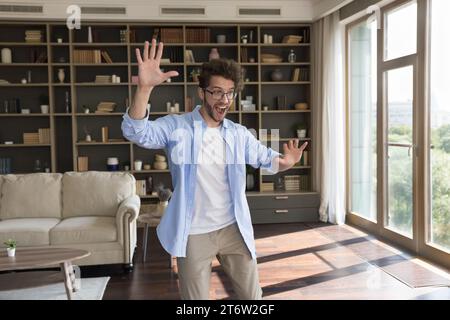 Cheery millennial single man having fun, fooling, celebrate moving day Stock Photo