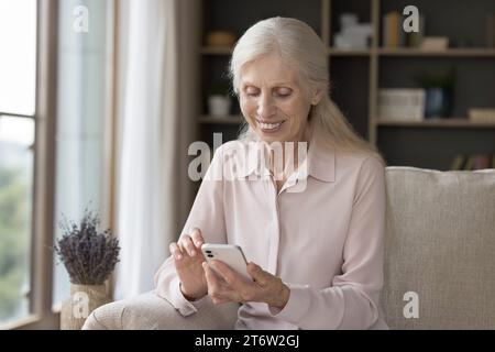 Satisfied mature female using modern smart phone Stock Photo