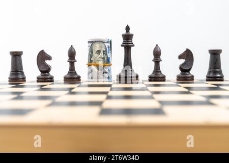 Chess game and rolled dollar bills as chess figure queen on board. . High quality photo Stock Photo