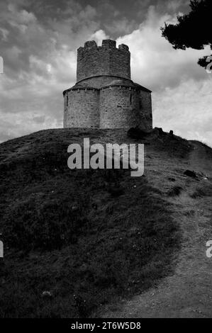 Monochrome photograph.  Fortress-like church of stone rubble, the Church of Saint Nicholas, near Nin in Zadar County, North Dalmatia, Croatia.  Built on a prehistoric mound to a trefoil plan in the late 1000s or early 1100s and the only example of pre-Romanesque architecture in Dalmatia.  A central battlemented watchtower was added in the 1500s AD when the church was fortified during a 100-year conflict between the Kingdom of Croatia and the Ottoman Empire. Stock Photo