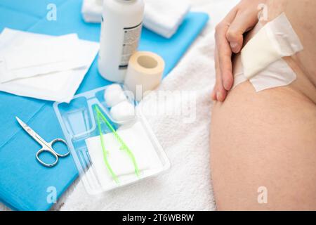 Close up view of hand touching wound with gauze on hip and Aid Kit utensils Stock Photo