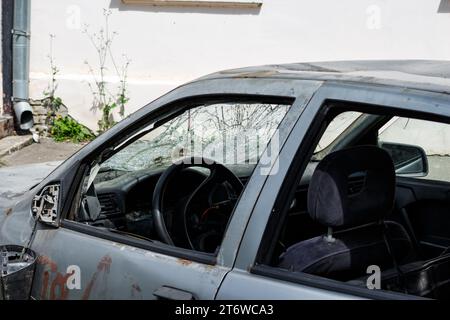 An old car with a broken windshield and traces of vandalism on the body, a broken rear view mirror Stock Photo