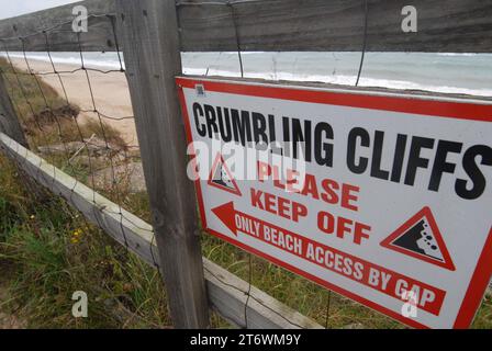 Historical photo of sign on fence warning beach-goers to keep off crumbling cliffs weakened by coastal erosion. Southern Marrams. Hemsby Stock Photo