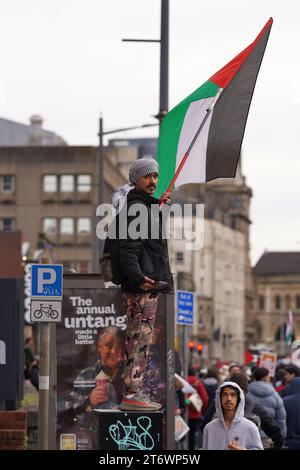 Muslim man stood up high waving his flag at the Pro Palestine March in Cardiff City Centre, Saturday 11th November 2023 Stock Photo