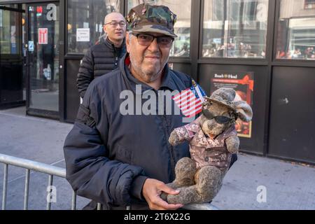 NEW YORK, NEW YORK - NOVEMBER 11: A spectator holds a puppet dress in uniform in the annual Veterans Day Parade on November 11, 2023 in New York City. Hundreds of people lined 5th Avenue to watch the biggest Veterans Day parade in the United States. This years event included veterans, active soldiers, police officers, firefighters and dozens of school groups participating in the parade which honors the men and women who have served and sacrificed for the country. Stock Photo