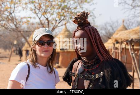 august  22, 2023: People of the Himba tribe in Namibia - traditional hairstyle, leather necklaces, and ochre tinted skin paste Stock Photo