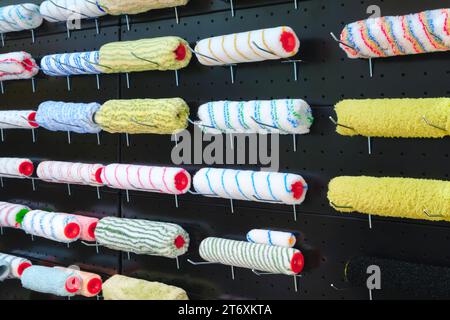 Multi-colored painter roller  for repairing black wall painting hang on a stand in a store for home decoration and repair. Stock Photo