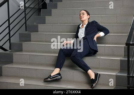 Woman fallen down stairs suffering from pain in back indoors Stock Photo