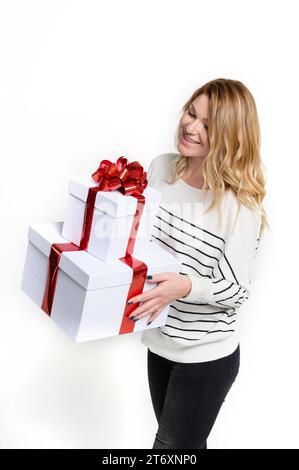 Happy young woman with white gift boxes on white background. Beautifully decorated for Christmas. Holiday fashion. Sales and shopping. Stock Photo