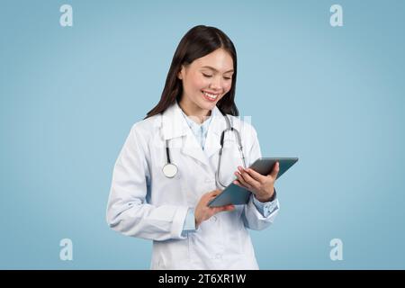 Young female doctor using digital tablet, smiling Stock Photo