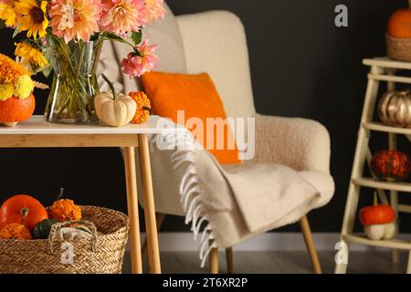 Room decorated with pumpkins and bright flowers, space for text. Autumn vibes Stock Photo